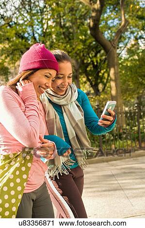 Twins walking and using smartphone in park View Large Photo Image Stock Image - Twins walking and using smartphone in park. Fotosearch