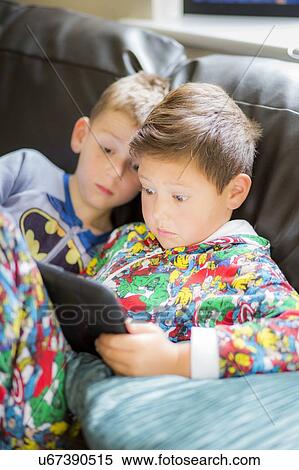 Two boys using a digital tablet View Large Photo Image Stock Photography - Two boys using a digital tablet. Fotosearch