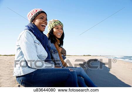 Two female friends relaxing at beach in winter View Large Photo Image Stock Image - Two female friends relaxing at beach in winter. Fotosearch