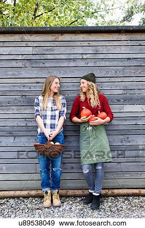 Two friends holding homegrown produce by wooden shed View Large Photo Image Stock Photo - Two friends holding homegrown produce by wooden shed. Fotosearch