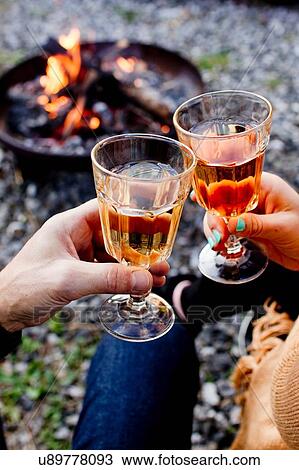 Stock Image - Two people toasting with drinks in wine glasses. Fotosearch