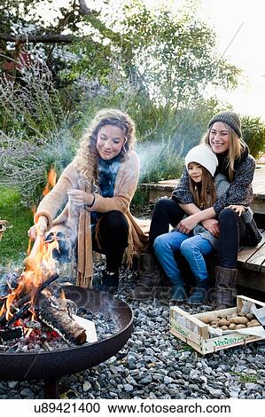 Two women and girl sitting by fire pit, relaxing View Large Photo Image Stock Image - Two women and girl sitting by fire pit, relaxing. Fotosearch