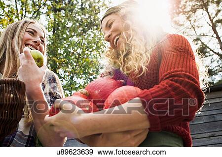 Two women holding homegrown produce, low angle View Large Photo Image Stock Photo - Two women holding homegrown produce, low angle. Fotosearch
