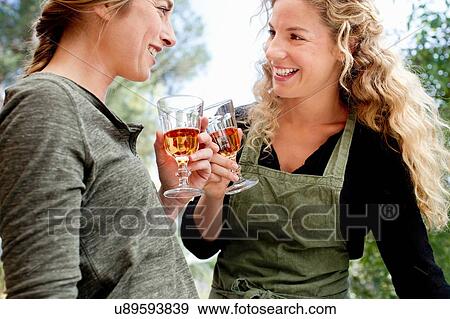 Two women toasting with wine glasses View Large Photo Image Stock Photo - Two women toasting with wine glasses. Fotosearch