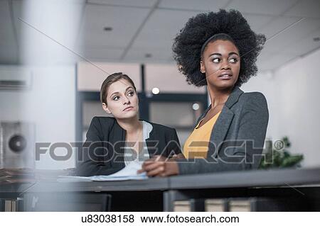 Two young businesswomen distracted at office reception View Large Photo Image Stock Photo - Two young businesswomen distracted at office reception. Fotosearch