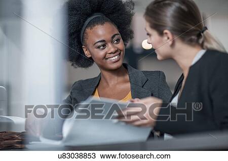 Two young businesswomen meeting at office reception View Large Photo Image Stock Image - Two young businesswomen meeting at office reception. Fotosearch