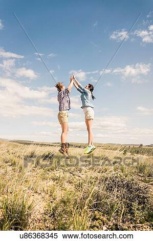 Two young women jumping and high fiving mid air, Bridger, Montana, USA View Large Photo Image Stock Photography - Two young women jumping and high fiving mid air, Bridger, Montana, USA. Fotosearch