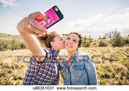 Two young women taking smartphone selfie with kiss on cheek, Bridger, Montana, USA View Large Photo Image Stock Image - Two young women taking smartphone selfie with kiss on cheek, Bridger, Montana, USA. Fotosearch