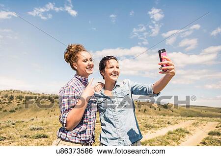 Two young women taking smartphone selfie on dirt track, Bridger, Montana, USA View Large Photo Image Stock Photograph - Two young women taking smartphone selfie on dirt track, Bridger, Montana, USA. Fotosearch
