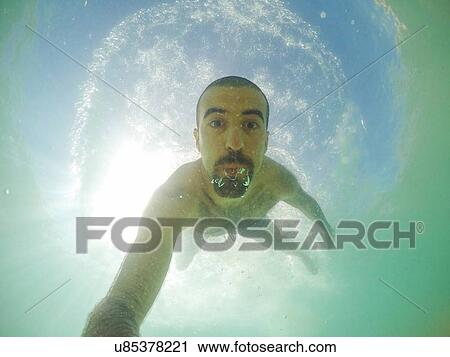 Stock Image - Underwater selfie of young man swimming in sea. Fotosearch