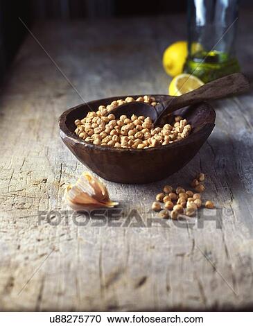 Stock Image - Vintage bowl and wooden spoon with raw chick peas and garlic cloves. Fotosearch