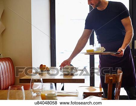 Stock Photo - Waiter clearing table in restaurant. Fotosearch
