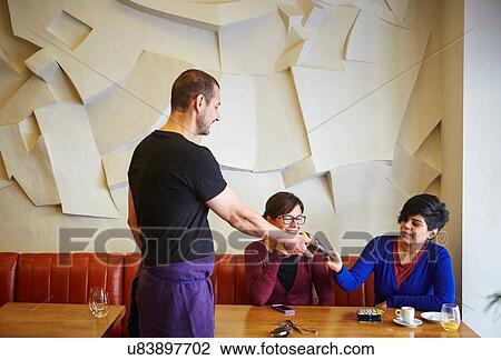 Waiter handing credit card machine to woman in restaurant View Large Photo Image Stock Image - Waiter handing credit card machine to woman in restaurant. Fotosearch