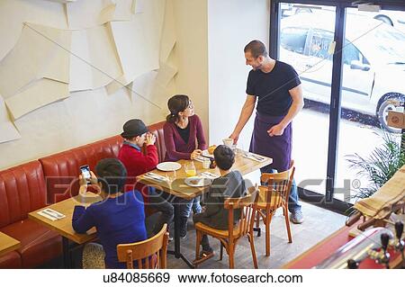 Waiter serving lunch in restaurant to family with boys View Large Photo Image Stock Photo - Waiter serving lunch in restaurant to family with boys. Fotosearch