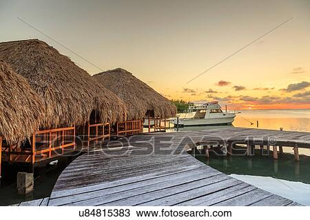 Stock Image - "Waterfront chalets and moored motor boat, St. Georges Caye, Belize, Central America". Fotosearch