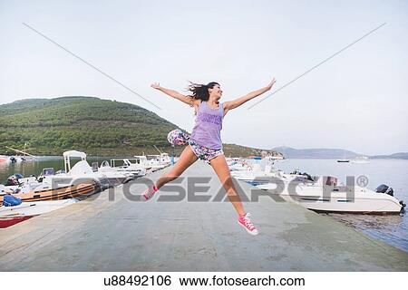 Woman at coast, jumping in mid air View Large Photo Image Stock Photograph - Woman at coast, jumping in mid air. Fotosearch