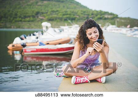 Woman at coast, looking at smartphone View Large Photo Image Stock Image - Woman at coast, looking at smartphone. Fotosearch