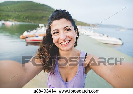 Picture - Woman at coast, taking a picture of herself. Fotosearch