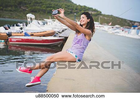Woman at coast, taking selfie with smartphone View Large Photo Image Stock Image - Woman at coast, taking selfie with smartphone. Fotosearch