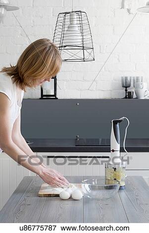 Stock Photo - Woman baking with flour and eggs at kitchen table. Fotosearch