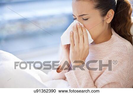 Stock Image - Woman blowing her nose. Fotosearch