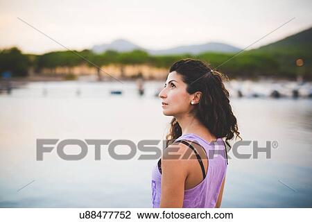 Stock Image - Woman by the sea, looking up. Fotosearch
