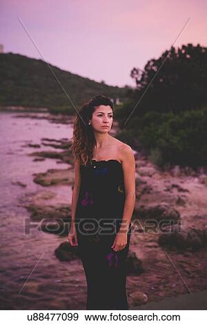 Stock Photo - Woman by the sea, wearing long dress. Fotosearch