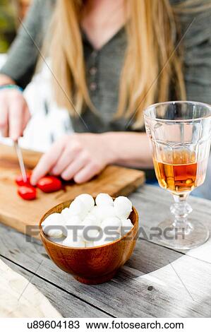 Woman chopping tomatoes with drink in glass in foreground View Large Photo Image Stock Image - Woman chopping tomatoes with drink in glass in foreground. Fotosearch