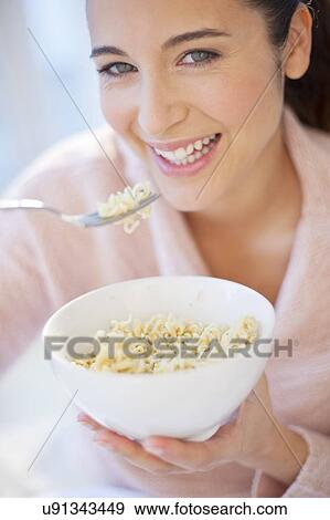 Stock Photo - Woman eating bowl of noodles. Fotosearch