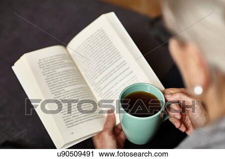 Stock Image - Woman having coffee and reading. Fotosearch