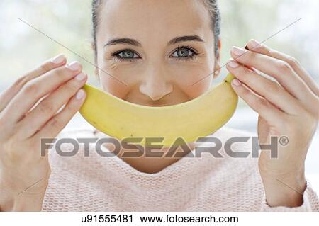 Woman holding a banana in front of face View Large Photo Image Stock Image - Woman holding a banana in front of face. Fotosearch