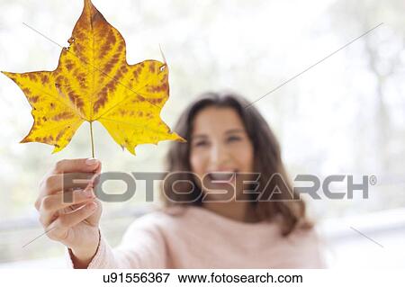 Stock Photo - Woman holding an autumn leaf. Fotosearch