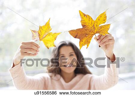 Stock Photograph - Woman holding autumn leaves. Fotosearch