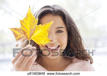 Stock Photo - Woman holding leaf in front of face. Fotosearch
