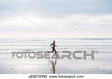 Stock Photo - Woman in bikini jogging on beach. Fotosearch