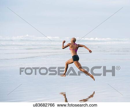 Woman in bikini sprinting on beach View Large Photo Image Stock Photograph - Woman in bikini sprinting on beach. Fotosearch