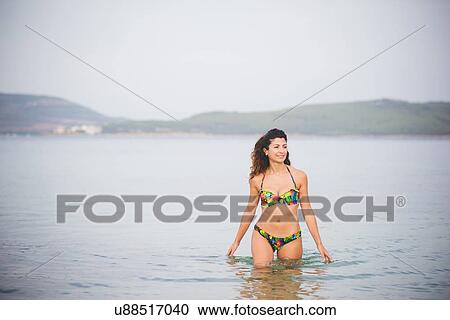 Stock Image - Woman in the sea, wearing bikini. Fotosearch