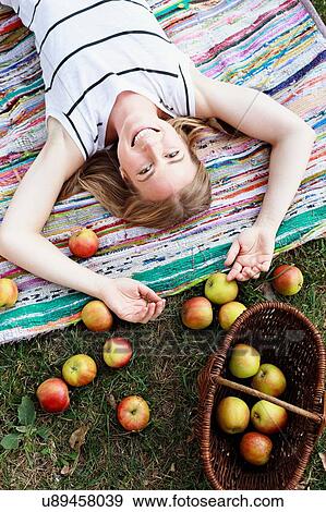 Woman lying on striped rug with basket of apples View Large Photo Image Stock Photo - Woman lying on striped rug with basket of apples. Fotosearch
