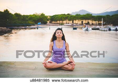Stock Photography - Woman meditating at coast. Fotosearch