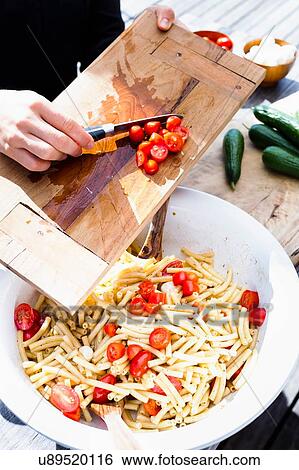 Stock Photograph - Woman scraping tomatoes into bowl with knife. Fotosearch