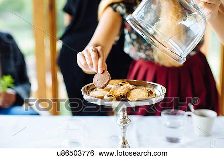 Stock Photograph - Woman selecting biscuit from cake stand in restaurant, Italy. Fotosearch