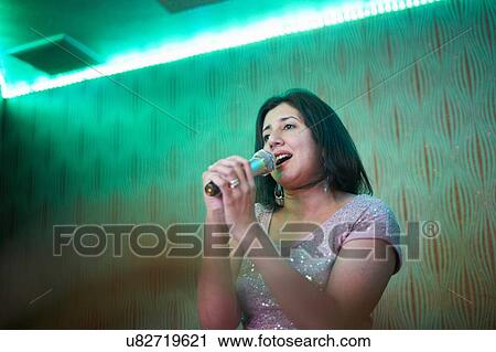 Stock Image - Woman singing karaoke. Fotosearch