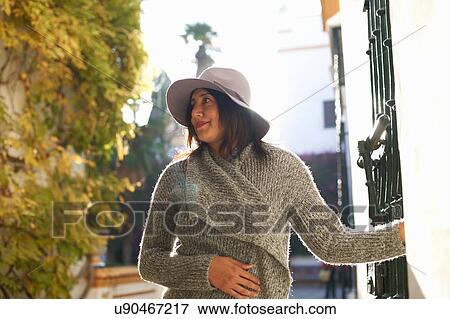 Stock Photo - Woman standing beside gated building, Seville, Spain. Fotosearch