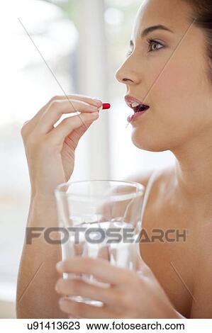 Stock Image - Woman taking a capsule. Fotosearch