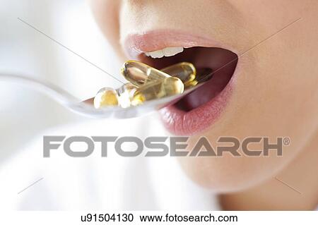 Stock Image - Woman taking vitamin supplements. Fotosearch