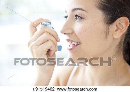 Stock Image - Woman using an inhaler. Fotosearch