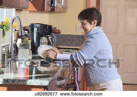Woman using crutches in her kitchen View Large Photo Image Stock Photo - Woman using crutches in her kitchen. Fotosearch