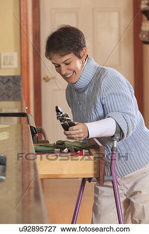 Woman using crutches in her kitchen View Large Photo Image Stock Photo - Woman using crutches in her kitchen. Fotosearch
