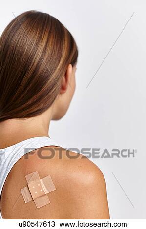 Stock Image - Woman with plaster on back of right shoulder. Fotosearch