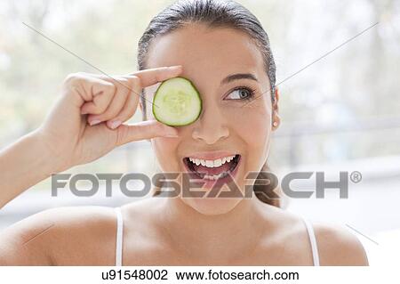 Stock Image - Woman with slice of cucumber. Fotosearch
